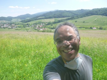Abie Louis KRIEG auf einem Hügel, daneben sind andere Hügel und sogar Wälder, er schaut glücklich und zufrieden
